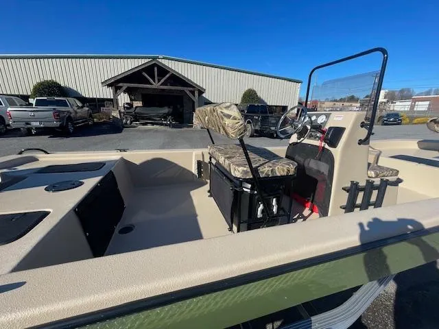 Slide: The Image of 2025 Carolina Skiff E20 JVX boat with camo seats, parked outdoors under clear blue sky. - 5