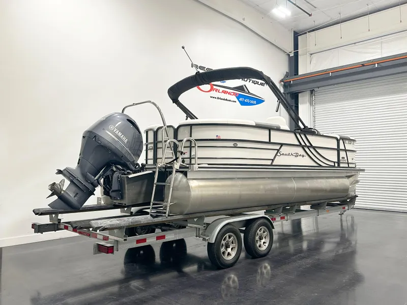Slide: The Image of 2022 South Bay 222RS pontoon boat on trailer in indoor storage. - 2