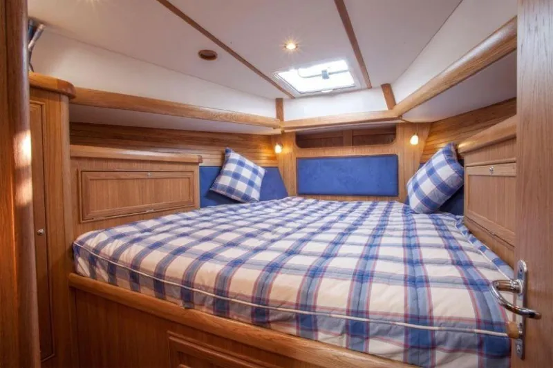 Slide: The Image of Luxurious cabin interior of 2025 Rustler 37 yacht with plaid bedding and wooden finish. - 18