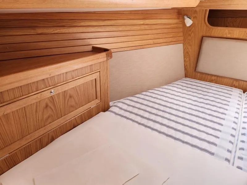 Slide: The Image of Cozy cabin interior of 2025 Rustler 37 yacht with wooden paneling and striped bedding. - 19