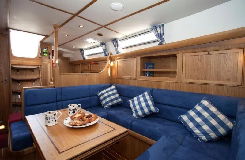 Slide: The Image of Interior of 2025 Rustler 37 yacht with blue seating and wooden accents. - 23