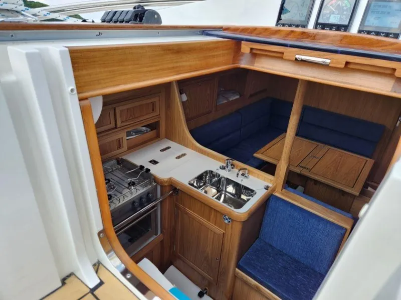 Slide: The Image of Interior of 2025 Rustler 37 yacht, featuring a compact kitchen and cozy seating area. - 29