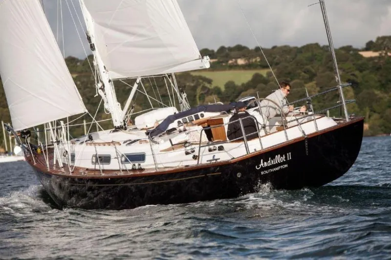 Slide: The Image of Sailing yacht Rustler 37, 2025 model, navigating coastal waters with lush green hills in background. - 3