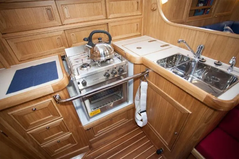 Slide: The Image of Compact wooden galley in 2025 Rustler 37 yacht with stove, sink, and storage. - 34