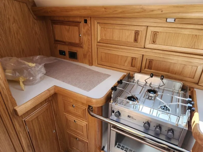 Slide: The Image of Rustler 37 (2025) yacht kitchen with wooden cabinetry and a modern stove. - 38