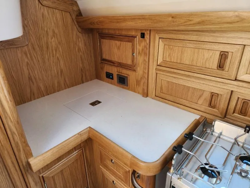 Slide: The Image of 2025 Rustler 37 yacht interior with wooden cabinetry and compact kitchen area. - 39