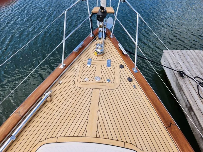 Slide: The Image of Bow of 2025 Rustler 37 yacht with teak deck, docked by water. - 8