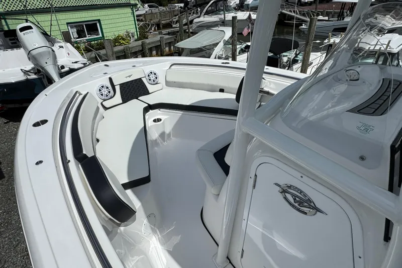 Slide: The Image of 2025 Tidewater 210 LXF boat interior with seating and console, docked at marina. - 13