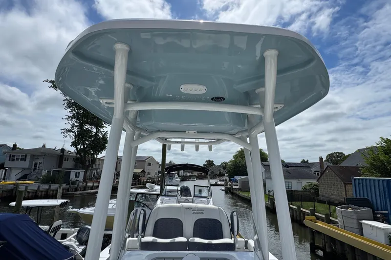 Slide: The Image of 2025 Tidewater 210 LXF boat with T-top, docked in a residential canal. - 18