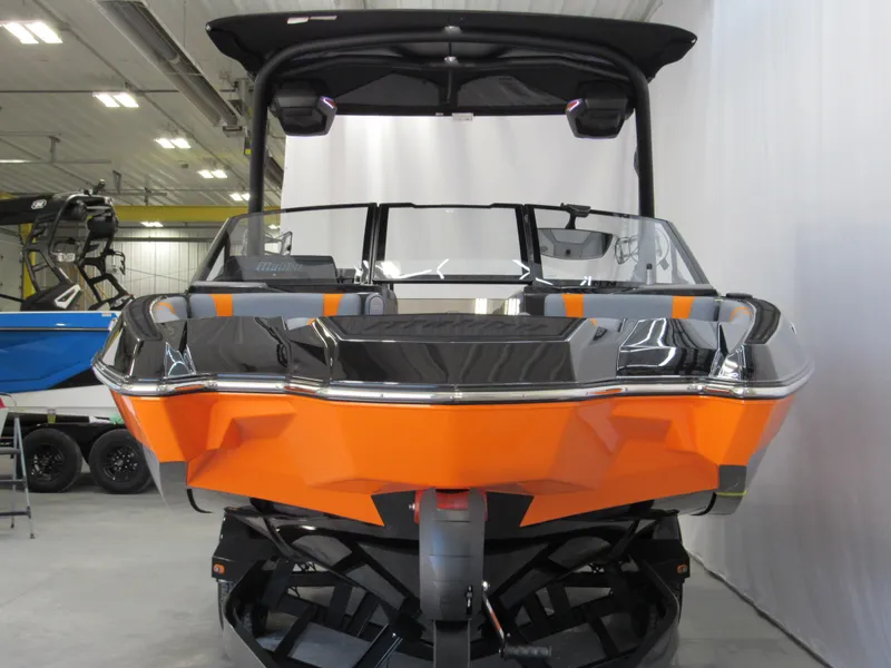 Slide: The Image of 2025 Malibu Wakesetter 22 MXZ boat in showroom, vibrant orange and black design. - 1