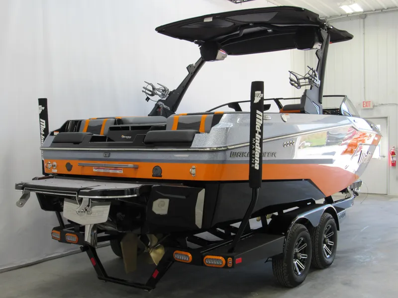 Slide: The Image of 2025 Malibu Wakesetter 22 MXZ boat, orange and black, in a showroom. - 4