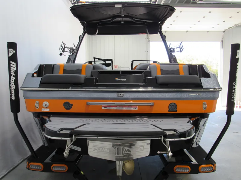 Slide: The Image of 2025 Malibu Wakesetter 22 MXZ boat, rear view, orange and black design in a showroom. - 5