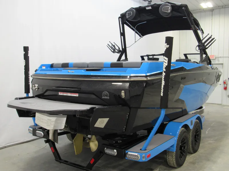 Slide: The Image of 2025 Axis A225 boat, blue and black, on a trailer in a garage. - 2