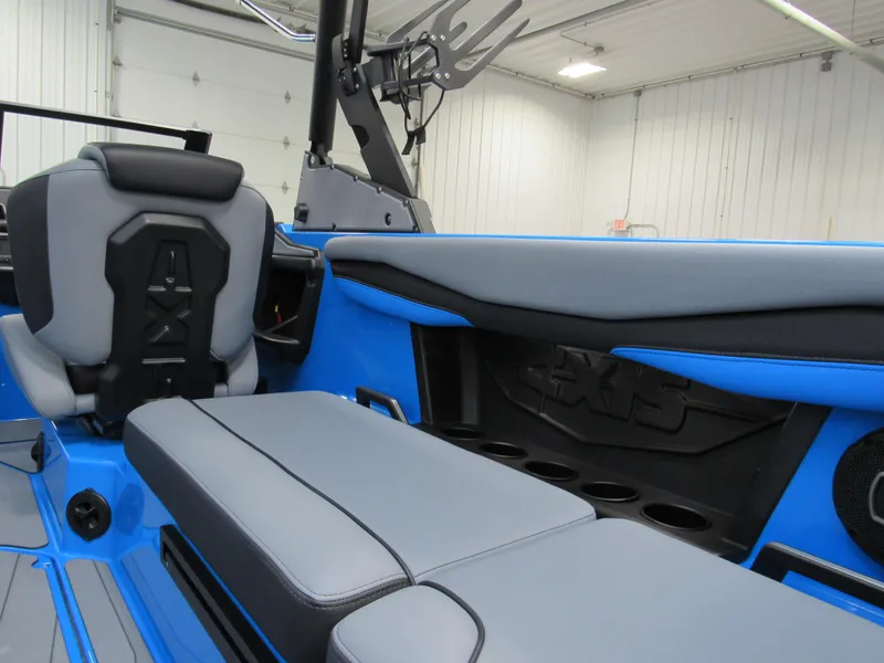 Slide: The Image of 2025 Axis A225 boat interior with blue and gray seating in a garage setting. - 7