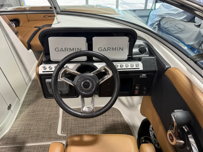 Slide: The Image of 2024 Crownline Eclipse E235 boat dashboard with Garmin displays and steering wheel. - 2