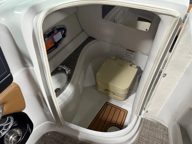 Slide: The Image of 2024 Crownline Eclipse E235 boat interior with compact bathroom and portable toilet. - 9