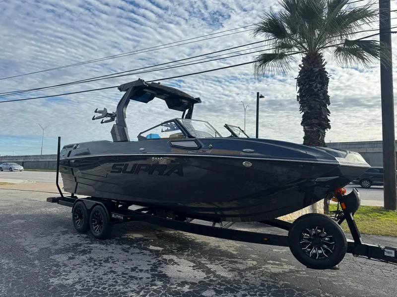 The Image of 2025 Supra SE 550 boat on trailer, parked near palm tree under cloudy sky. - 1