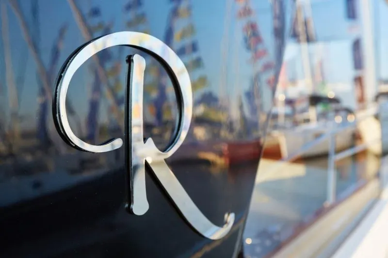 Slide: The Image of Close-up of Rustler 41 yacht logo, 2025 model, with marina reflections. - 13