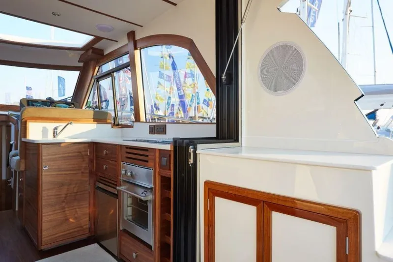 Slide: The Image of Interior of 2025 Rustler 41 yacht, featuring modern kitchen with wood cabinetry and stainless steel appliances. - 38