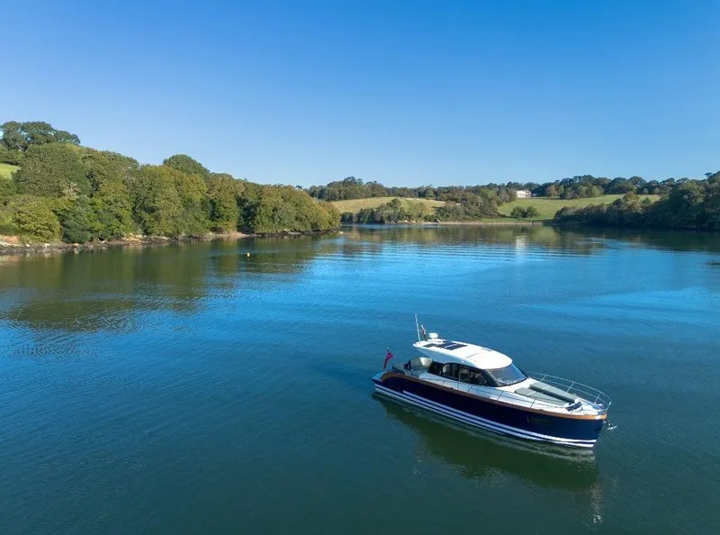 Slide: The Image of 2025 Rustler 41 boat cruising on a serene lake with lush green surroundings. - 5