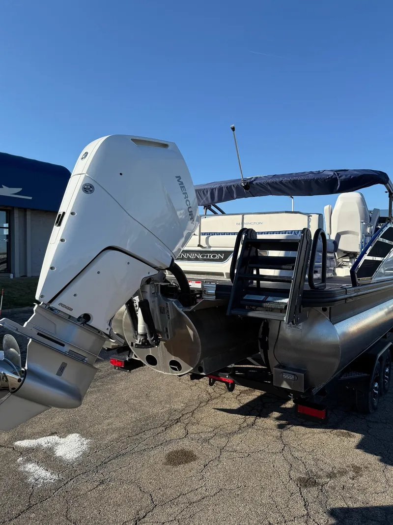 Slide: The Image of 2024 Bennington RX Sport Line boat with outboard motor, parked outdoors. - 8