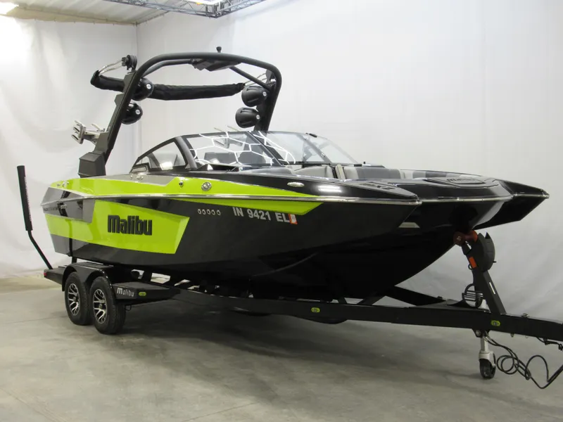 Slide: The Image of 2023 Malibu Wakesetter 23 MXZ boat in showroom, black and green design. - 2