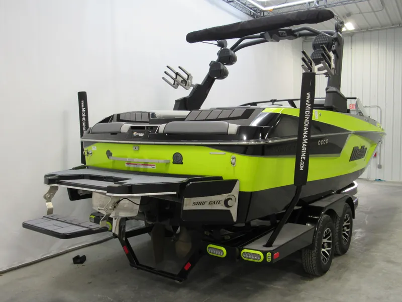 Slide: The Image of 2023 Malibu Wakesetter 23 MXZ boat, lime green and black, on trailer in a garage. - 3