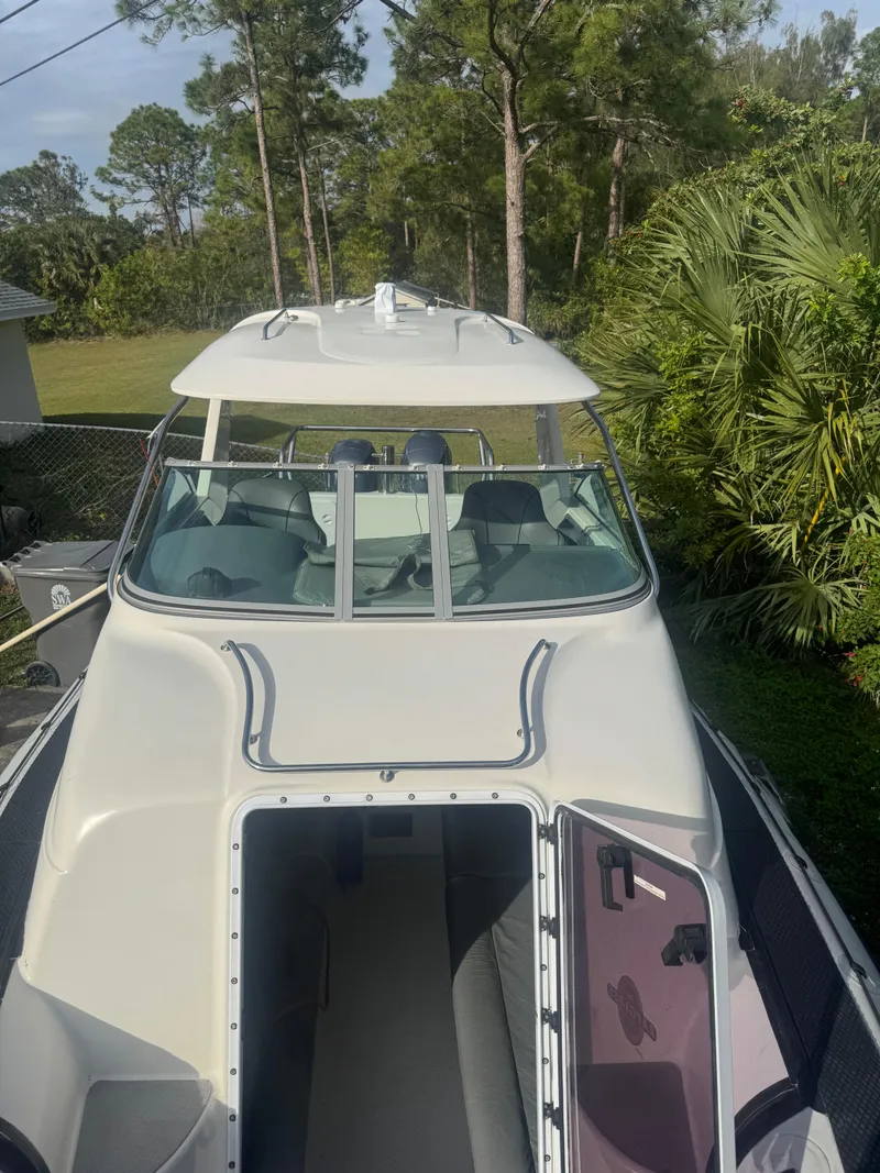 Slide: The Image of 2002 Protector 28 Targa boat with open cabin, surrounded by lush greenery. - 12