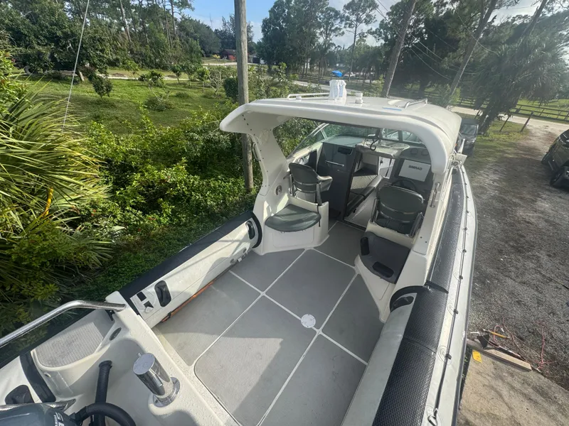 Slide: The Image of 2002 Protector 28 Targa boat interior with seating and controls, surrounded by greenery. - 6