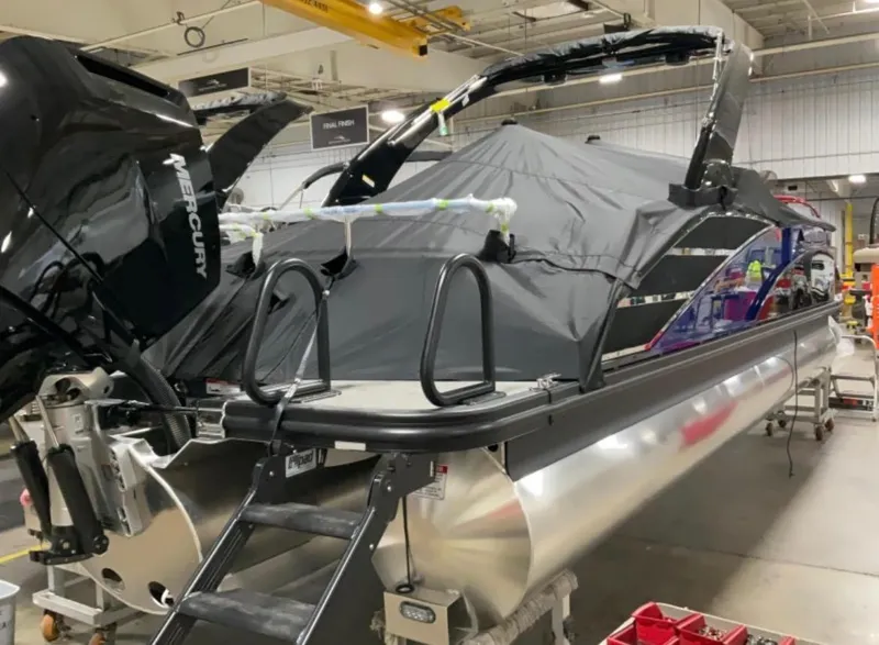 Slide: The Image of 2024 Bennington RX Sport Line boat in a workshop, covered and equipped with a Mercury engine. - 3