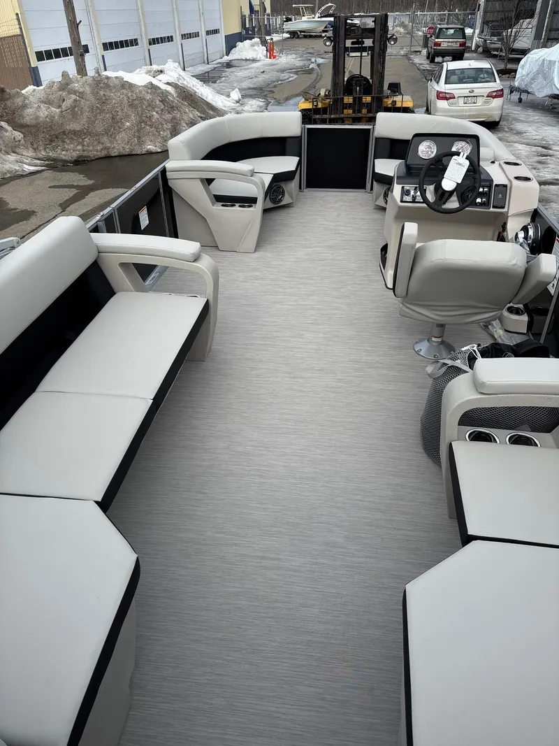 Slide: The Image of 2025 Harris Breeze 230 boat interior with modern seating and steering, parked in snowy urban area. - 14