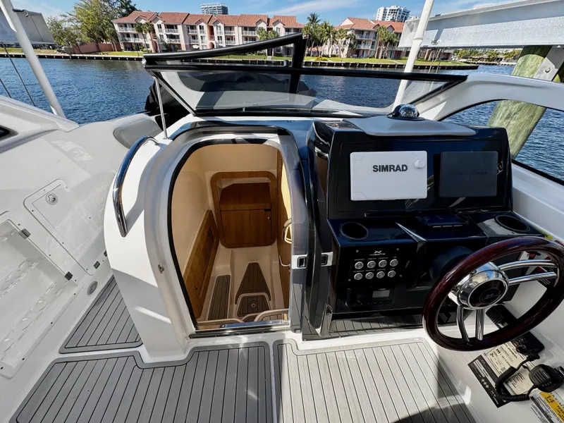 Slide: The Image of 2024 NX Boats 280 Xtreme cockpit with Simrad navigation system, open cabin door, waterfront view. - 13