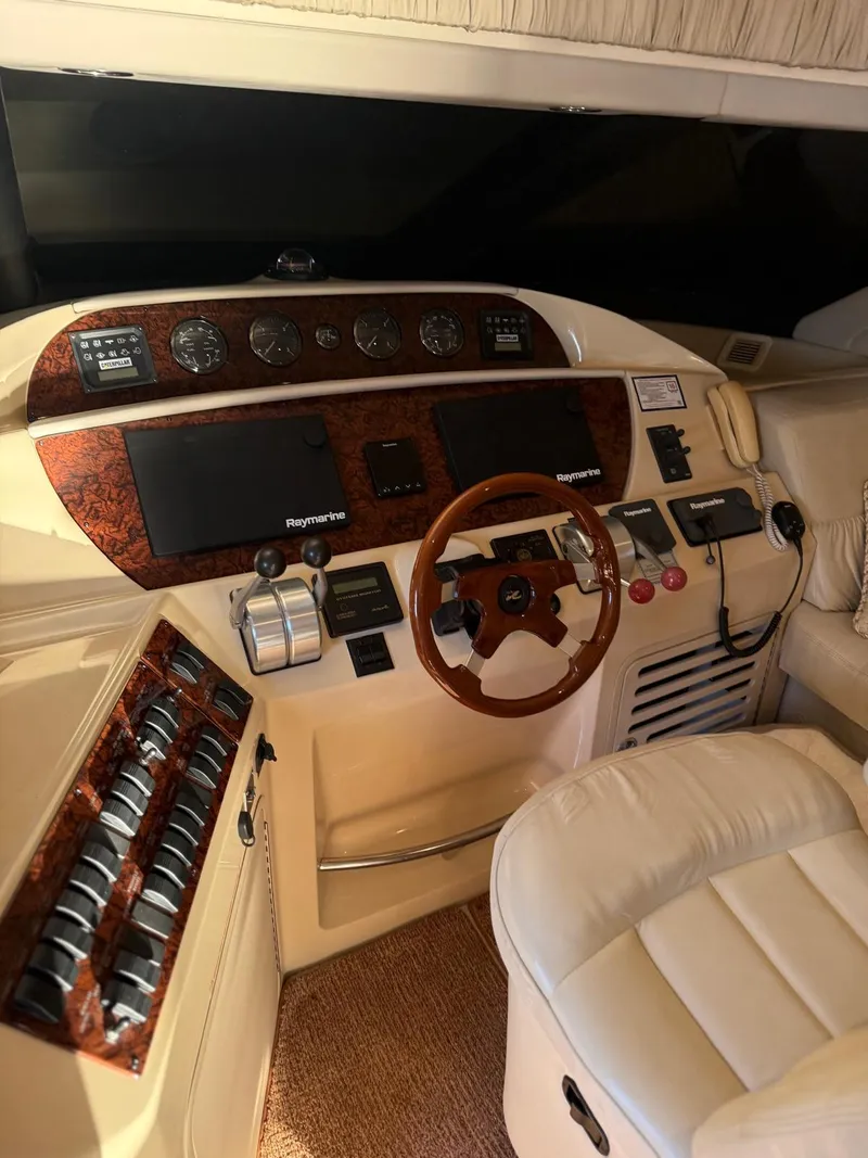 Slide: The Image of 2001 Sea Ray 540 Cockpit Motor Yacht helm with wood accents and leather seating. - 5