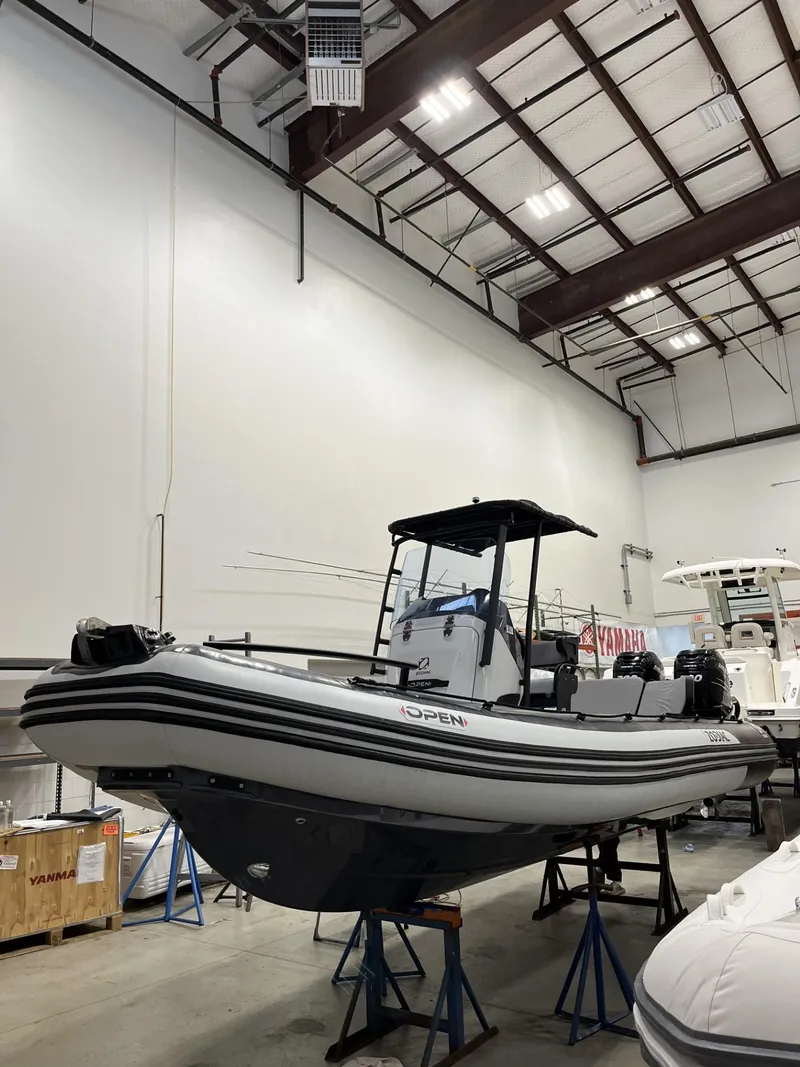Slide: The Image of 2024 Zodiac Open 6.5 boat displayed in a showroom, elevated on stands. - 2