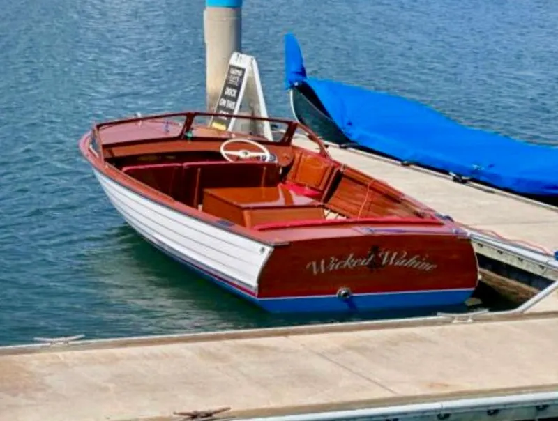 The Image of Classic 1956 custom boat by South Coast Boatyard docked on calm water. - 0