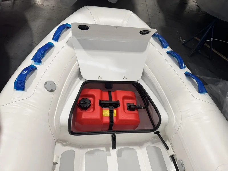 Slide: The Image of 2024 Zodiac Nomad 3.6 RIB Alu with open storage compartment and red fuel tank. - 3