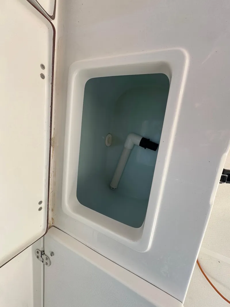 Slide: The Image of 2015 Sea Hunt Ultra 234 boat storage compartment with plumbing. - 13