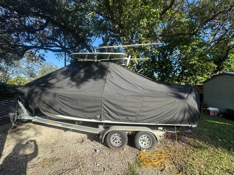 Slide: The Image of 2015 Sea Hunt Ultra 234 boat covered on trailer under trees. - 15