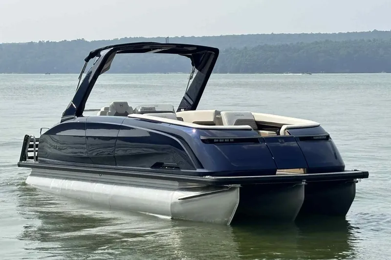 Slide: The Image of 2025 Harris Crowne SL 250 pontoon boat on calm lake waters. - 13