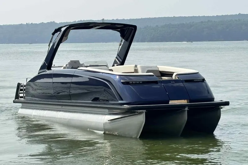 Slide: The Image of 2025 Harris Crowne SL 250 pontoon boat on calm lake waters. - 14