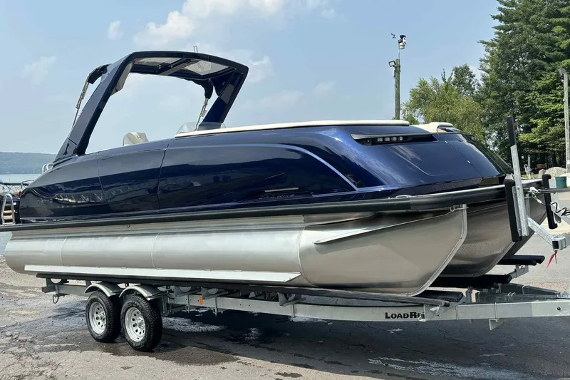 Slide: The Image of 2025 Harris Crowne SL 250 pontoon boat on trailer, sleek design, blue exterior. - 15