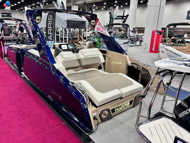 Slide: The Image of 2025 Harris Crowne SL 250 luxury pontoon boat on display at a boat show. - 4