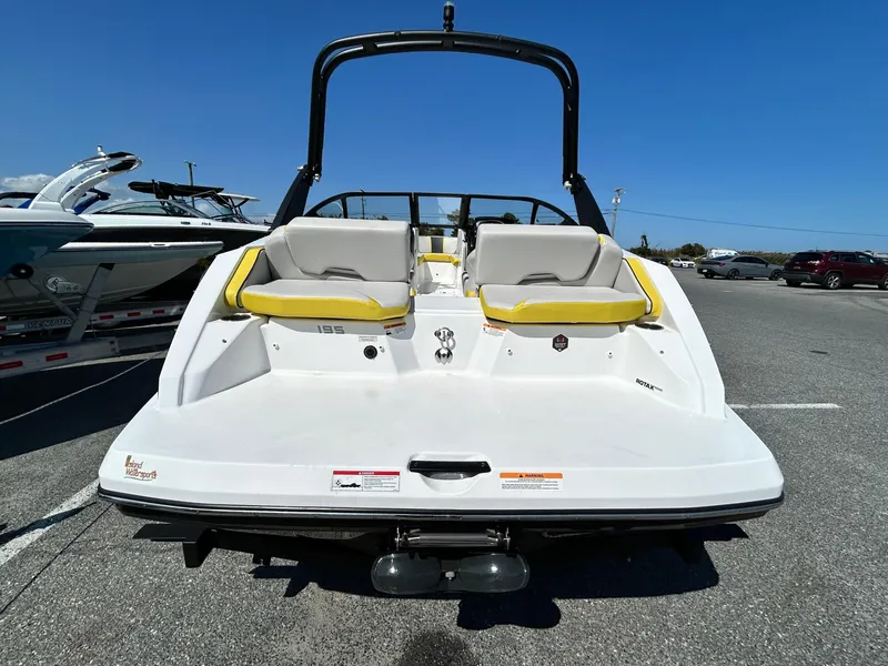 Slide: The Image of 2024 Scarab 195 ID boat, rear view, parked on asphalt under clear blue sky. - 13
