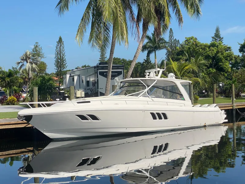 Slide: The Image of 2019 Intrepid 475 Sport Yacht docked by palm trees, reflecting on calm water. - 0