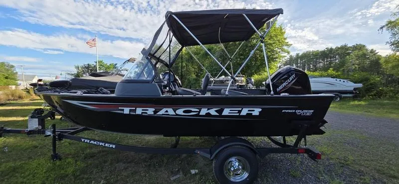 Slide: The Image of 2025 Tracker PG V16 WT boat with canopy on trailer, parked outdoors. - 11