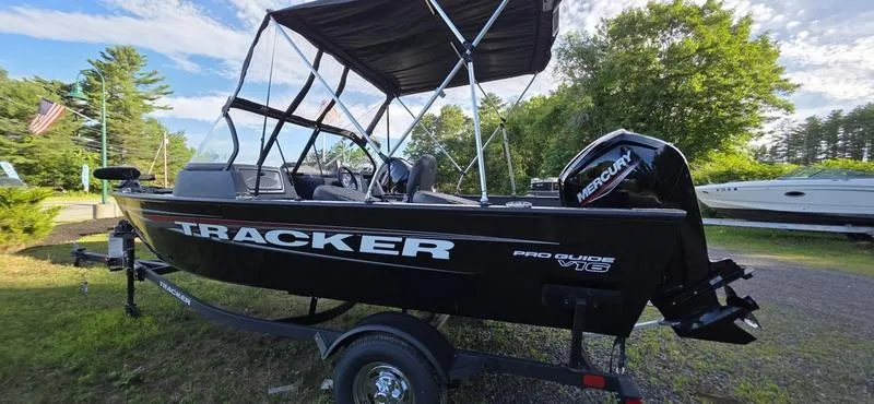 Slide: The Image of 2025 Tracker PG V16 WT boat with canopy and Mercury engine, parked outdoors. - 12