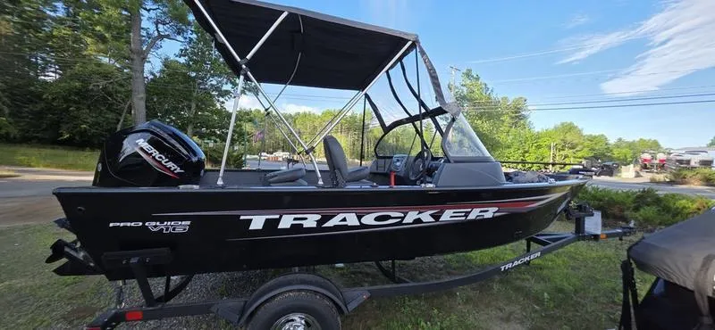 The Image of 2025 Tracker PG V16 WT boat with canopy on trailer, parked outdoors. - 2