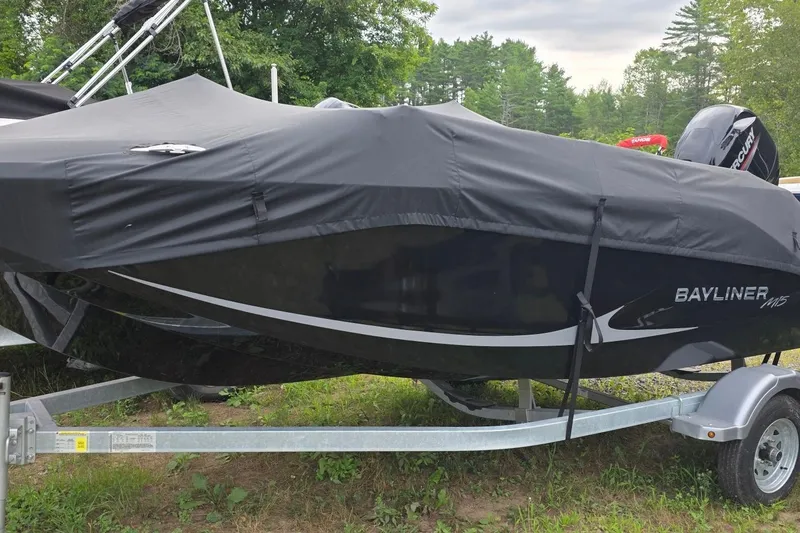 Slide: The Image of 2025 Bayliner M15 boat covered on a trailer, parked outdoors. - 1