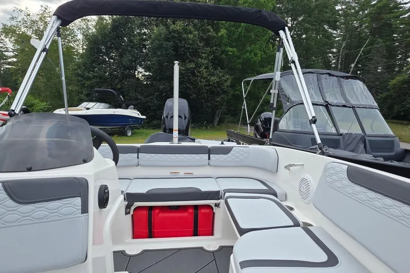 Slide: The Image of 2025 Bayliner M15 boat interior with seating, steering wheel, and canopy, set in a lush outdoor environment. - 11