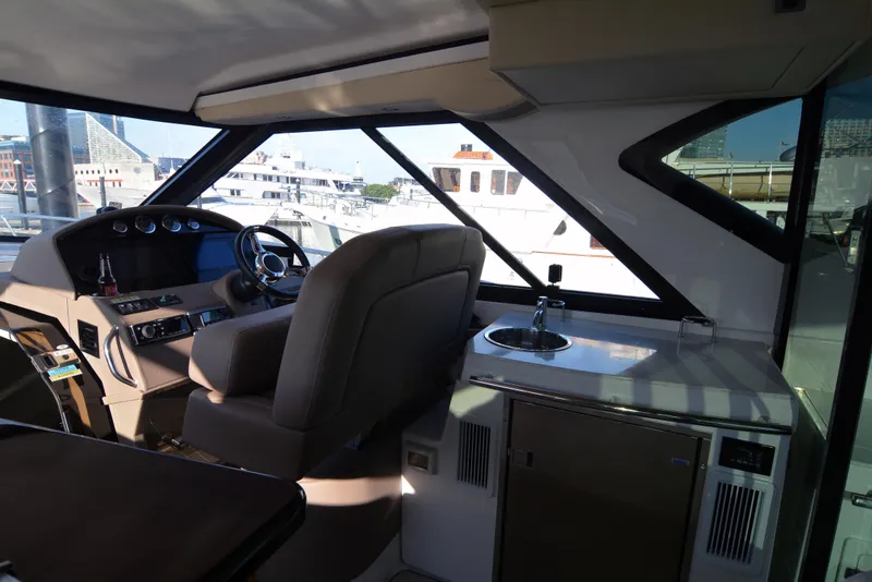 Slide: The Image of Interior of 2018 Regal 46 Sport Coupe yacht, featuring helm and kitchenette area. - 12